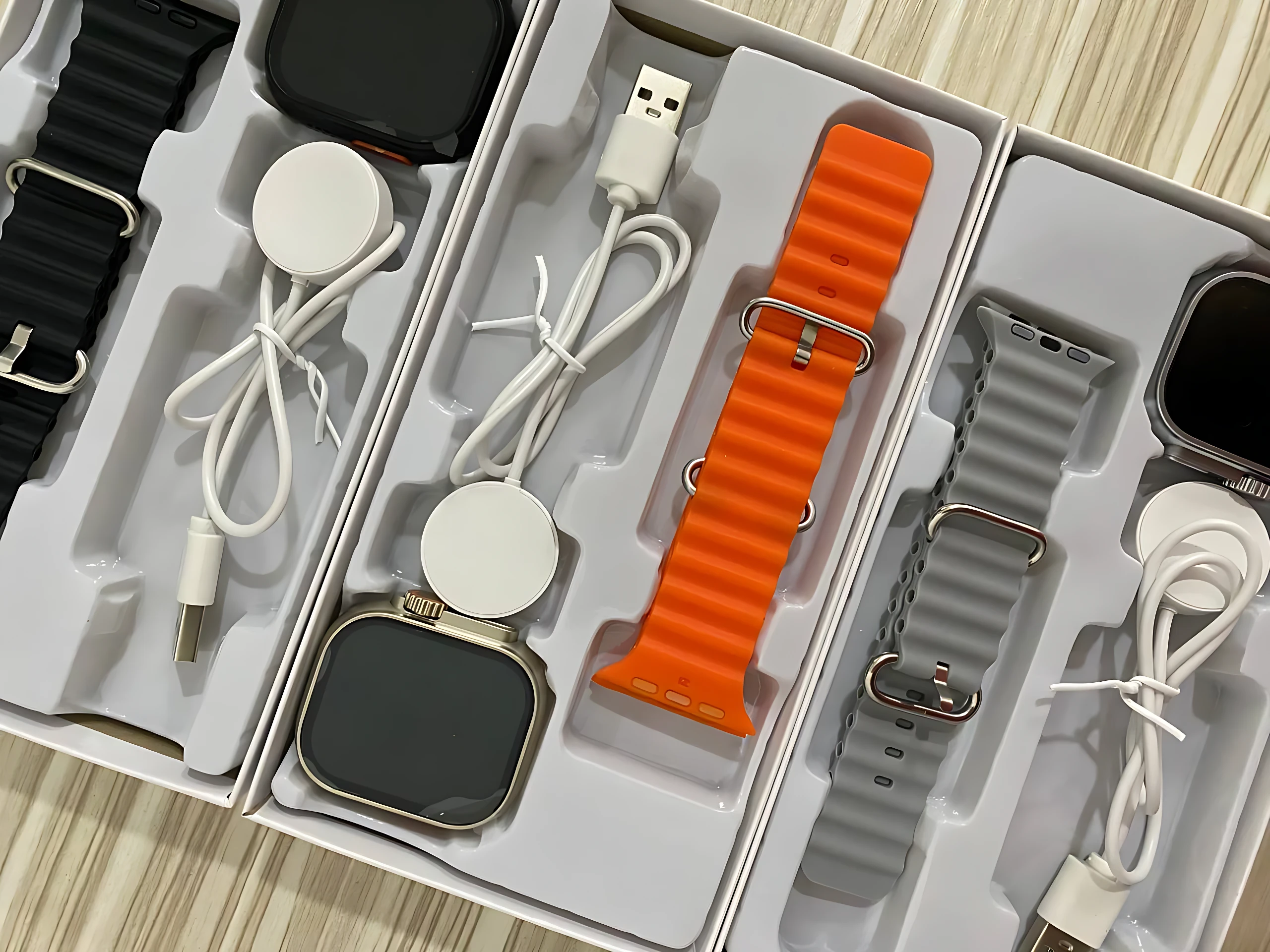 Vista superior de caja abierta con smartwatch C90 Ultra 2, correa naranja y gris, cargador y cable USB.