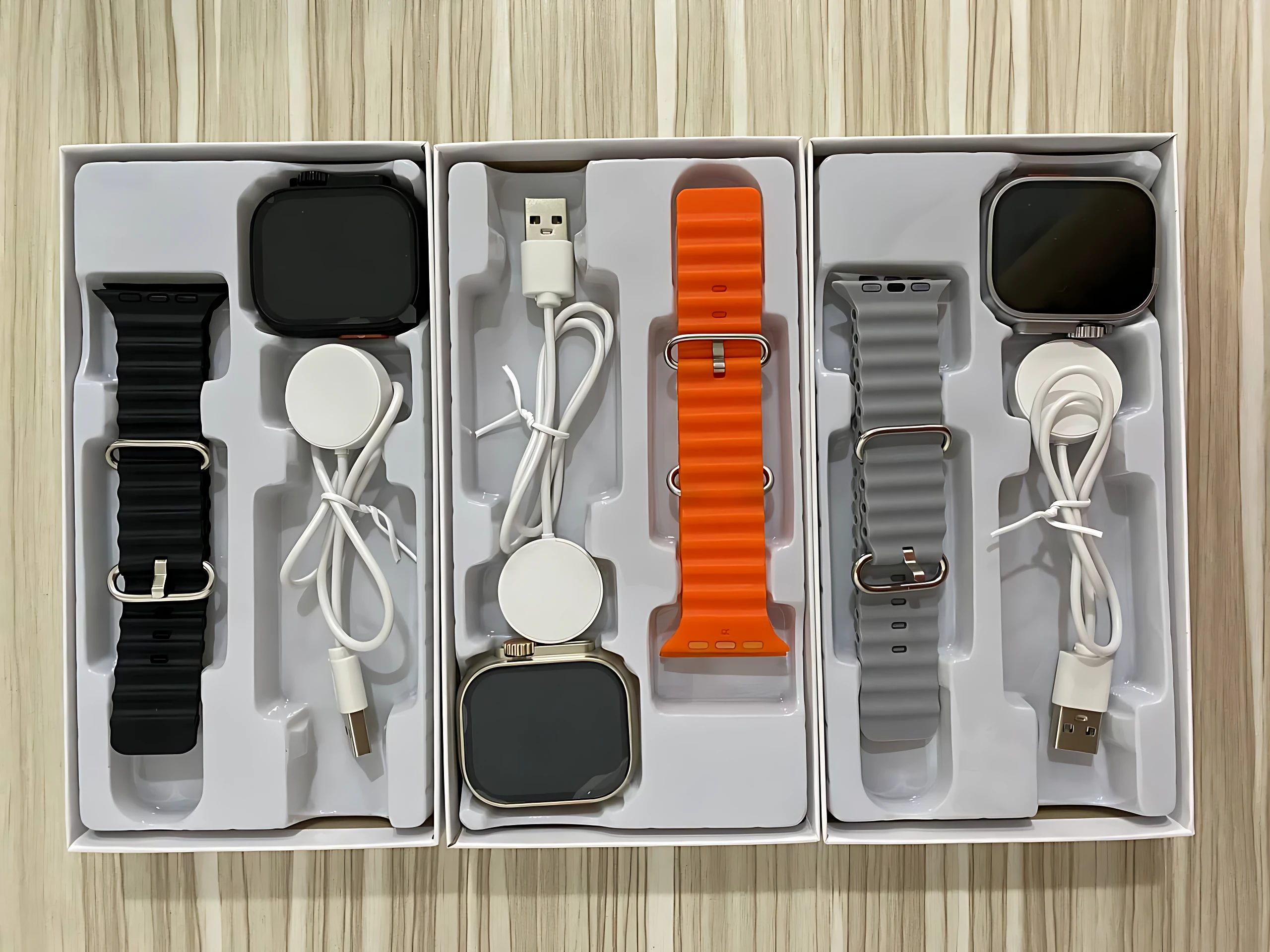 Tres cajas de reloj smartwatch C90 Ultra 2 con correas intercambiables en negro, naranja y gris, cada una con cargador y cable USB.
