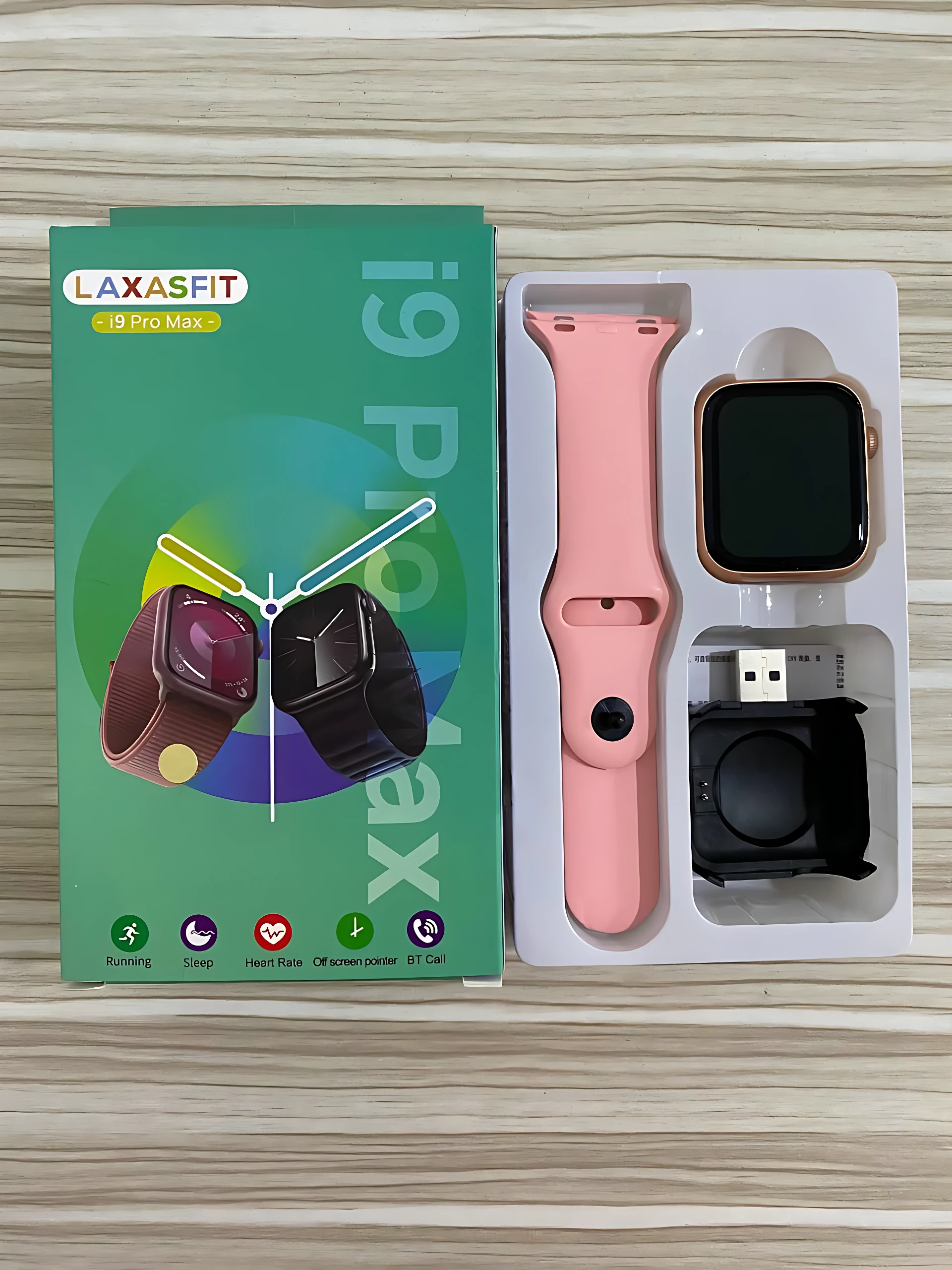 Reloj inteligente I9 Pro Max en caja abierta, mostrando correa rosa, pantalla negra, cargador y cable USB. Incluye caja verde con de variantes.
