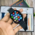 Smartwatch S10 Ultra 2 negro con pantalla encendida mostrando aplicaciones, sostenido en mano sobre caja abierta que incluye correas intercambiables y accesorios.