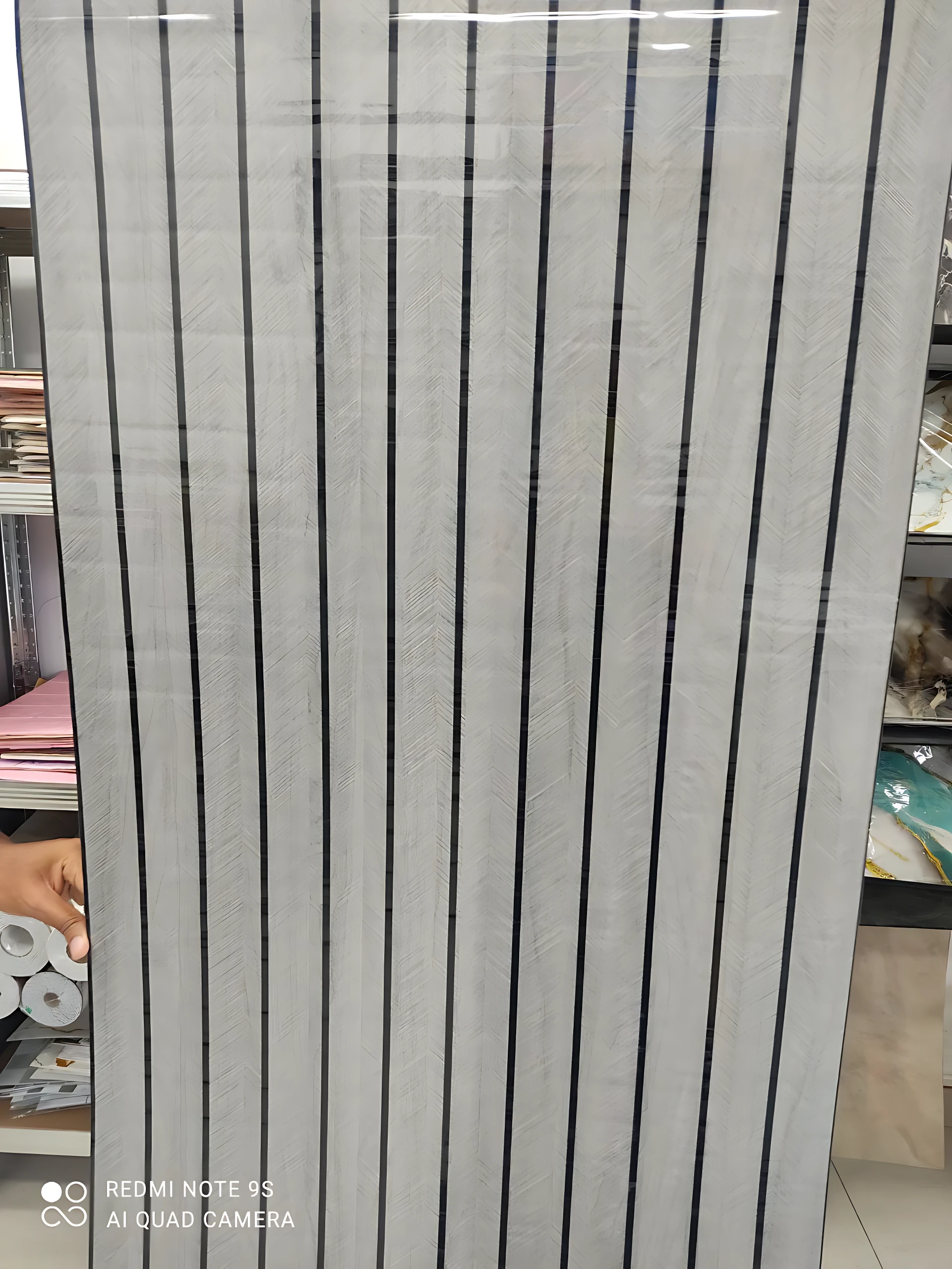 Rollo adhesivo pared acolchonado con diseño de rayas verticales negras sobre fondo blanco, textura lisa y acabado mate.