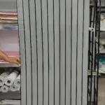 Rollo adhesivo pared acolchado con diseño de rayas verticales blancas y grises, textura suave y acabado mate, ideal para renovar muros sin obras mayores.