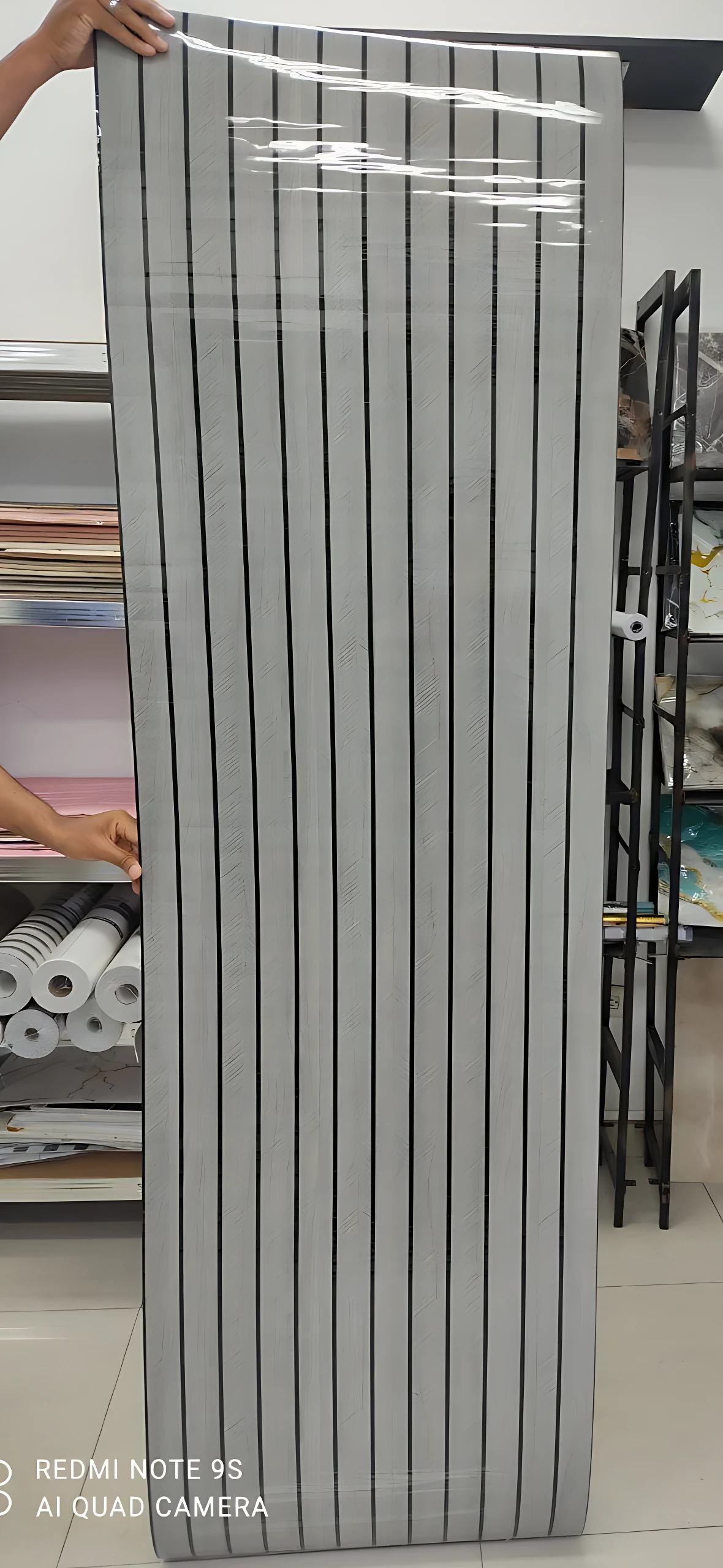 Rollo adhesivo pared acolchado con diseño de rayas verticales blancas y grises, textura suave y acabado mate, ideal para renovar muros sin obras mayores.