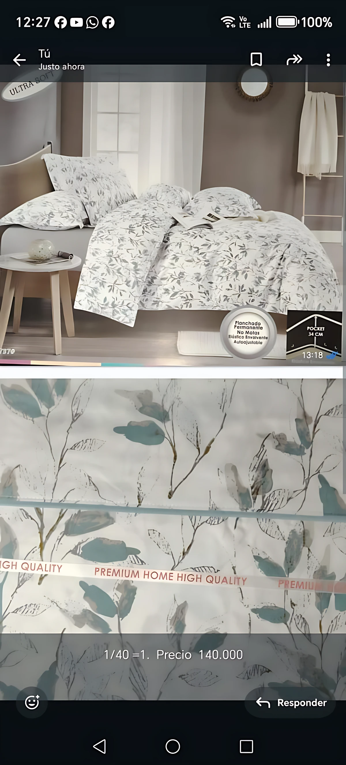 Colcha estampada floral doble faz en tonos claros con hojas verdes, vista frontal en cama con cojines y mesita lateral; incluye etiqueta de calidad premium.