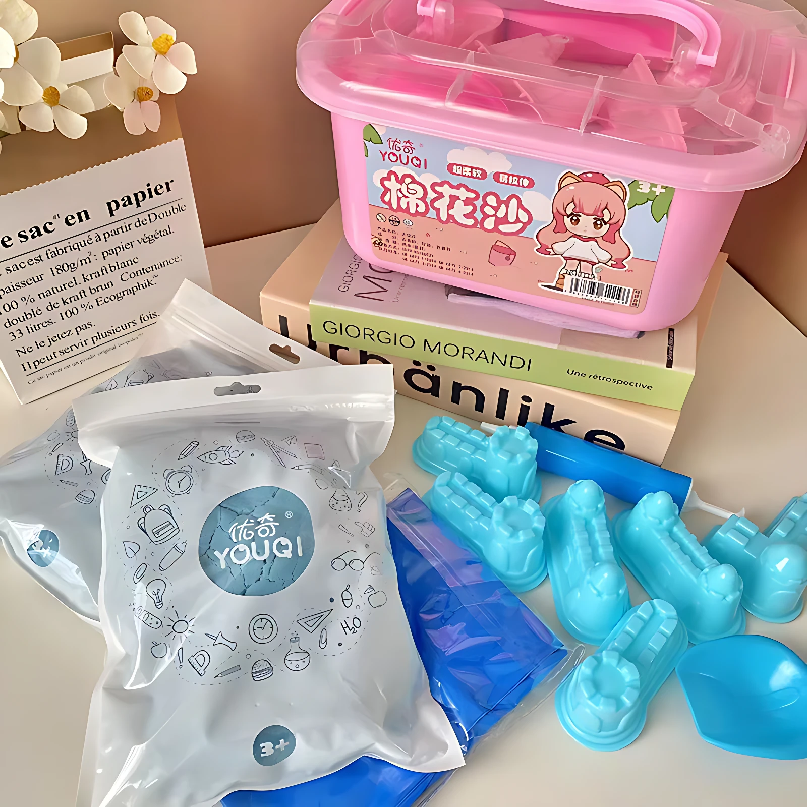 Set de arena mágica con moldes azules, contenedor rosa y accesorios para juego creativo infantil.