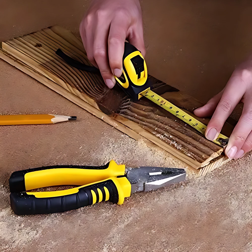 Manos midiendo tabla de madera con cinta métrica amarilla; destornillador amarillo y negro en primer plano, sobre superficie con virutas.