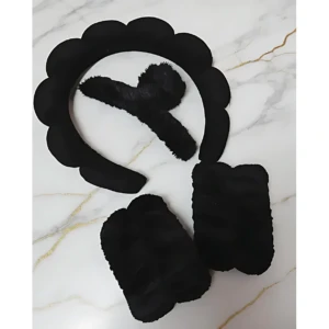 Set de tres accesorios negros de diadema con textura suave, dispuestos sobre fondo blanco con vetas doradas. Incluye diadema con forma de nube y dos piezas adicionales, todos en color negro.