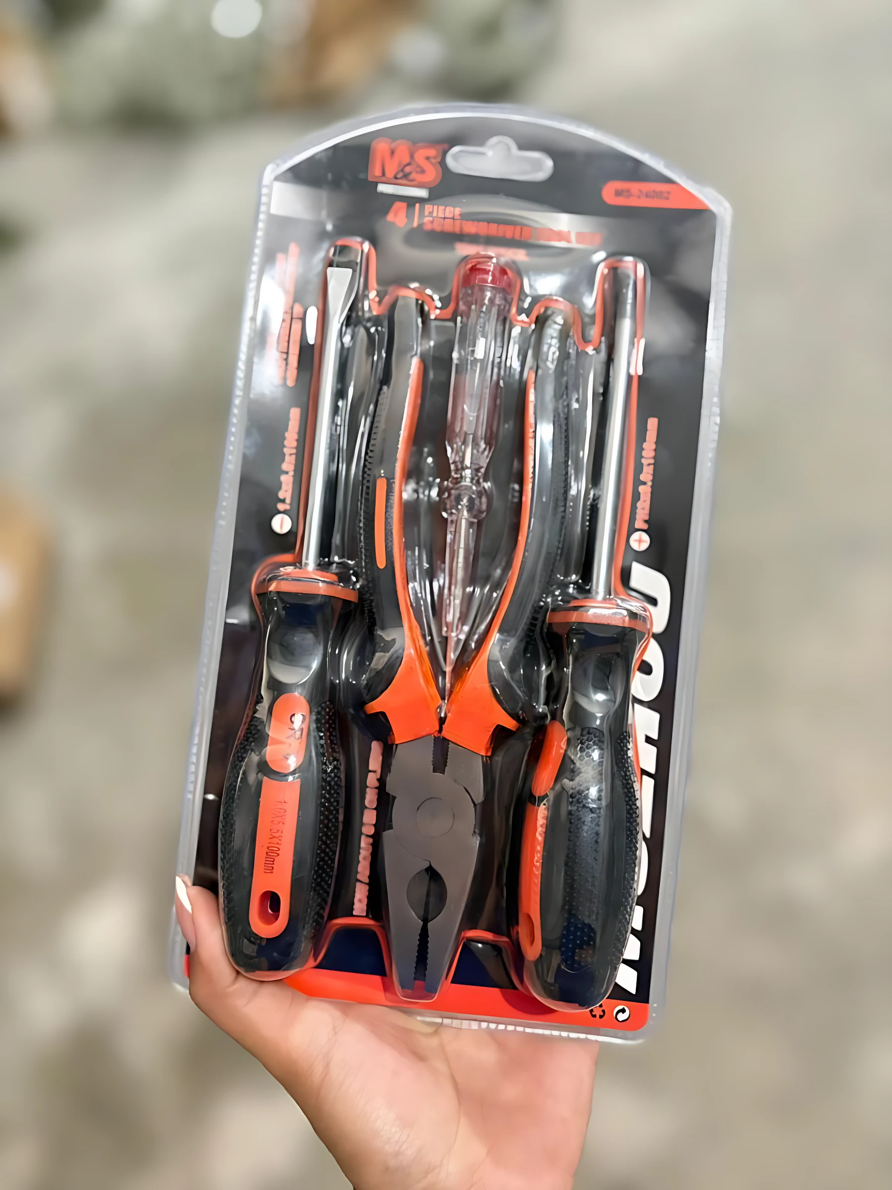 Set de cuatro herramientas de precisión con mango negro y naranja, incluyendo destornilladores y alicates, en empaque transparente con fondo blanco.