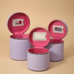 Set de tres neceseres circulares en lila con interior rosa y espejo integrado, ideales para maquillaje y viajes.