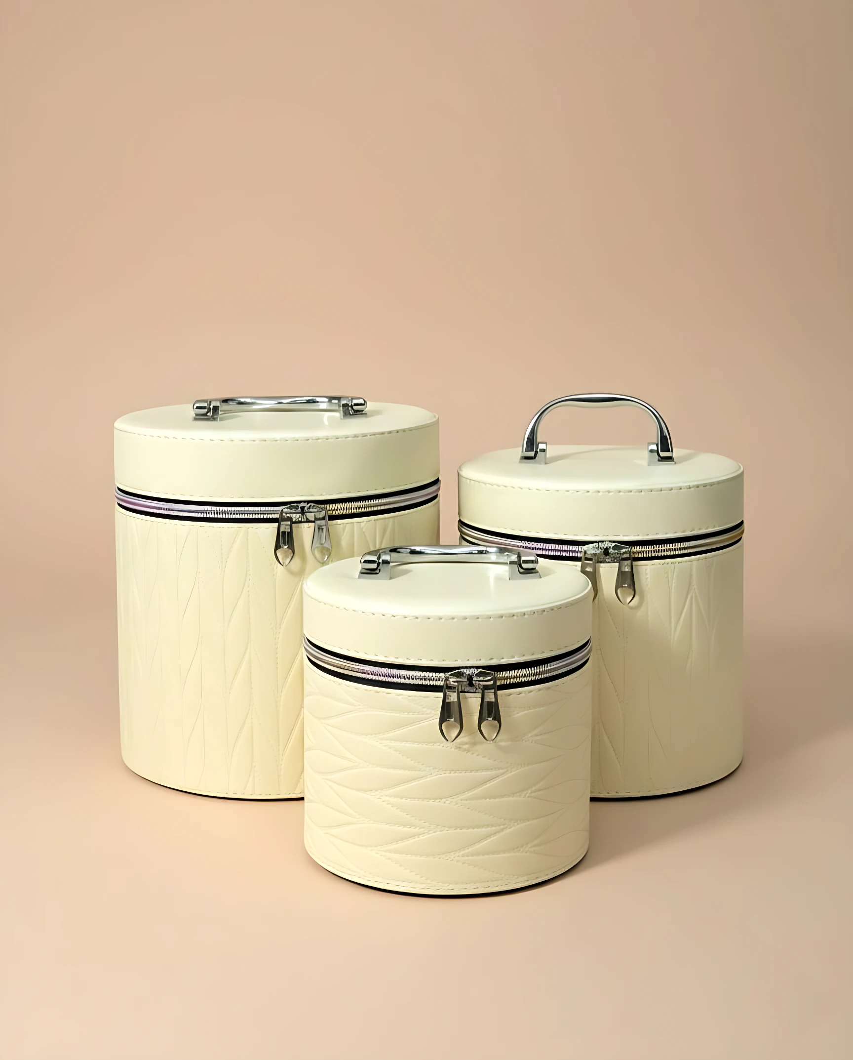 Set de tres neceseres circulares en color crema con textura de cuero, cierres metálicos y asas ergonómicas, ideales para organizar maquillaje y accesorios de viaje.