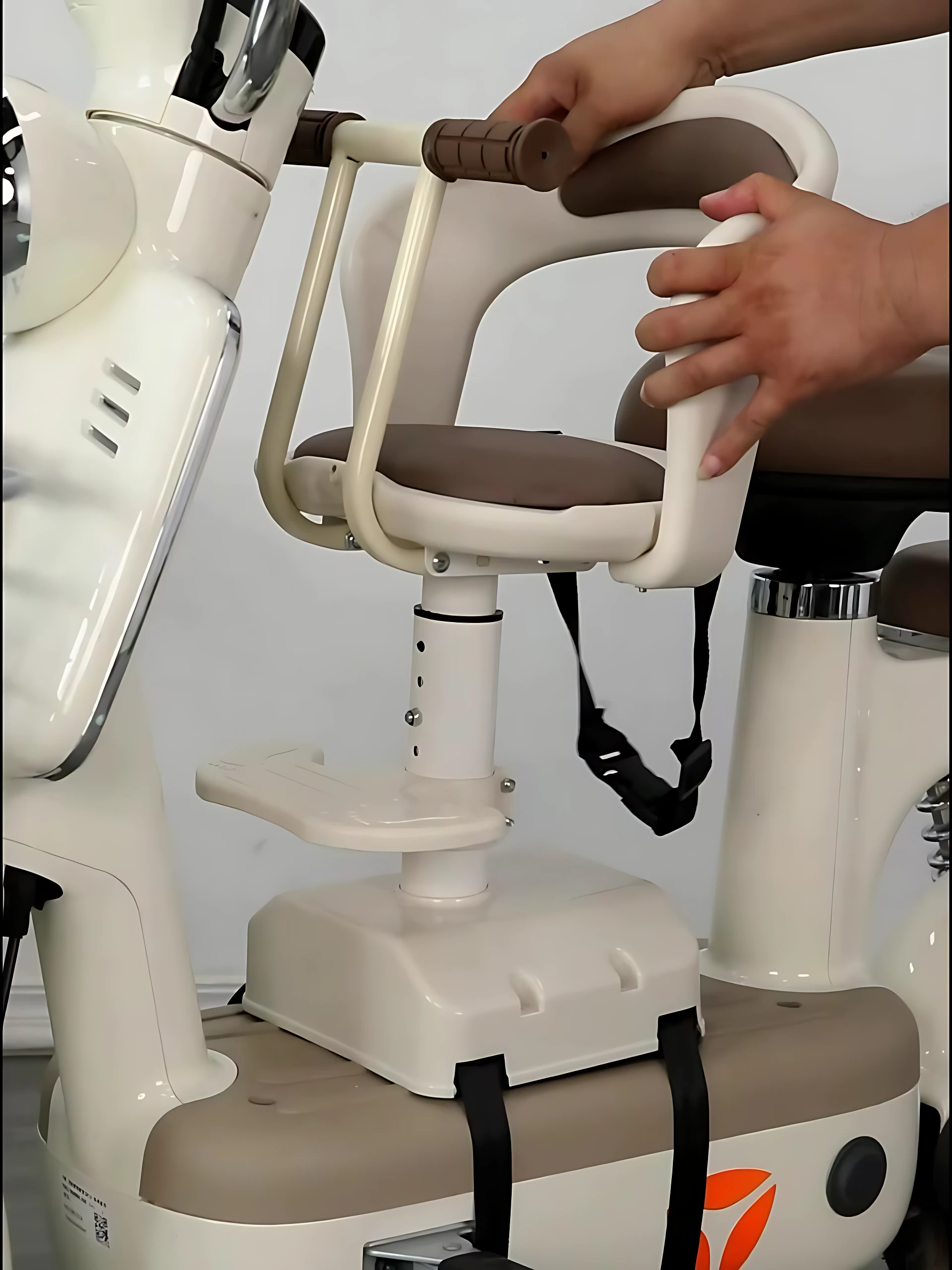 Silla infantil delantera para scooter en color blanco con asiento marrón, arnés negro ajustable y manillar ergonómico, montada sobre base fija con soporte de seguridad.