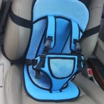 Silla de viaje para bebés en color azul claro con malla transpirable, arneses negros y base acolchada, instalada sobre asiento de coche beige.