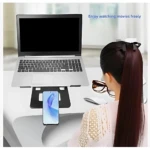 Soporte ergonómico metálico para laptop y tablet, en color negro, con compartimento inferior para móvil. Visto desde atrás, sobre escritorio blanco, junto a mujer con gafas y laptop abierta.