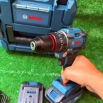 Taladro inalámbrico 12V Bosch de litio con reversibilidad, en uso sobre superficie verde artificial, acompañado de su caja azul y cargador.