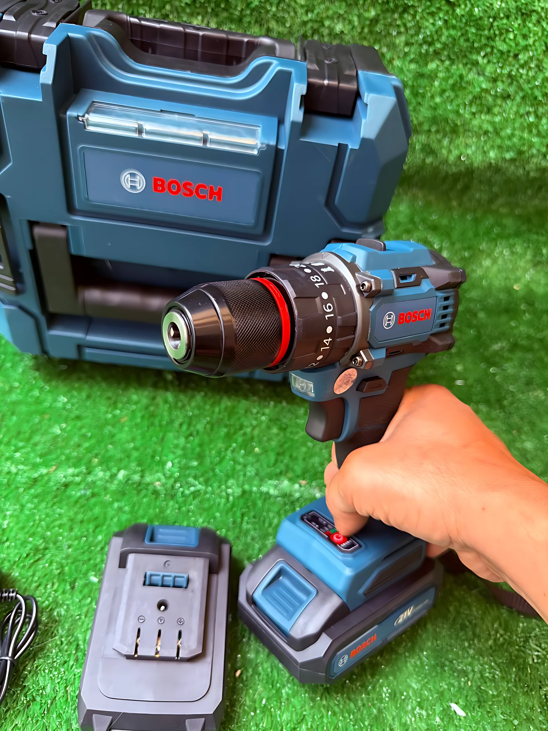 Taladro inalámbrico 12V Bosch de litio con reversibilidad, en uso sobre superficie verde artificial, acompañado de su caja azul y cargador.