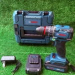 Taladro inalámbrico Bosch de 12V en color azul con caja de transporte, cargador y batería incluidos sobre fondo verde.