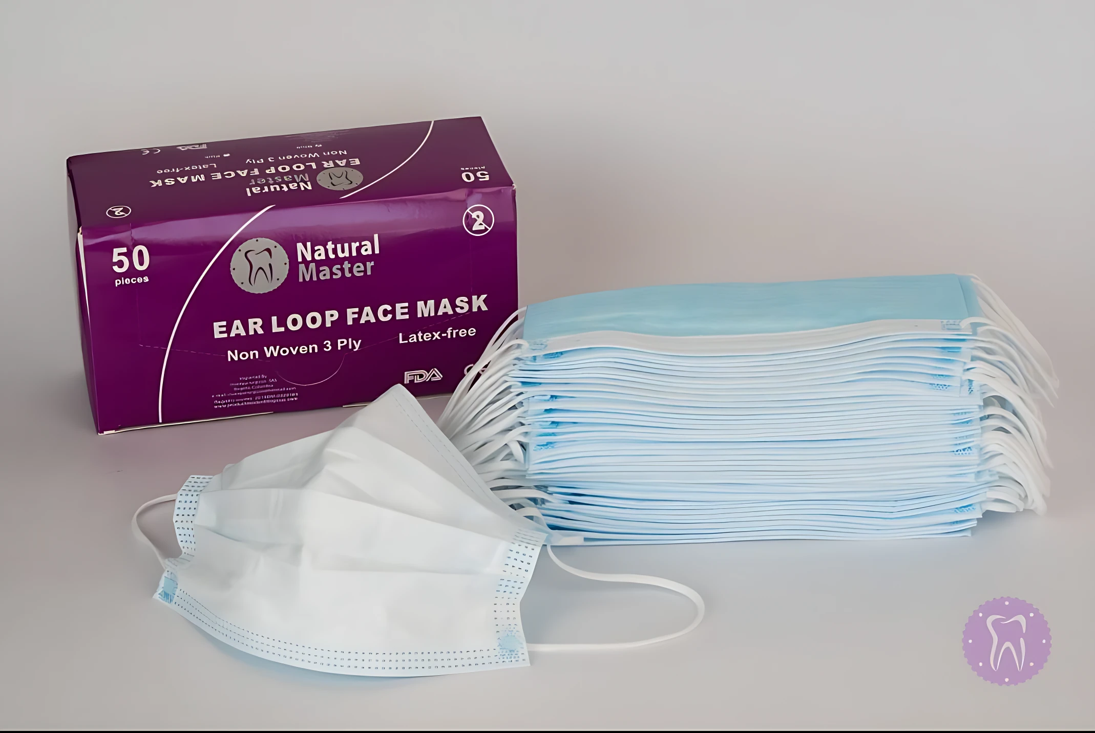 Caja morada de tapabocas quirúrgicos de tres capas, color azul claro, con 50 unidades. Se muestra una unidad desplegada al frente y un montón de tapabocas doblados detrás.