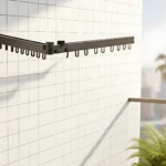 Tendedero plegable de metal negro mate montado en pared con rejilla, diseñado para secar ropa sin ocupar espacio en el suelo.