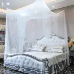 Toldillo cama doble malla blanca, instalado sobre cama con cabecero tapizado en blanco y detalles plateados, en habitación con iluminación cenital y piso de mármol negro.