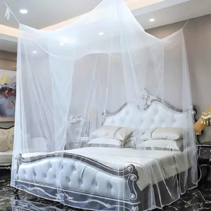 Toldillo cama doble malla blanca, instalado sobre cama con cabecero tapizado en blanco y detalles plateados, en habitación con iluminación cenital y piso de mármol negro.