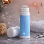Bálsamo para vellos encarnados de Amercar Lab en presentación roll-on con tapa removible, envase cilíndrico azul claro con cruz blanca, sobre superficie texturizada con accesorios de cuidado capilar al fondo.