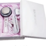 Dispositivo EMS infrarrojo ultrasonido en caja blanca con forro rosa, incluye mango blanco, cabezal redondo plateado, cable enrollado y accesorio cuadrado.