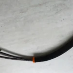 Cable de bloqueo para volante con carcasa negra y conectores naranjas, diseñado para fijar el volante y evitar su giro.