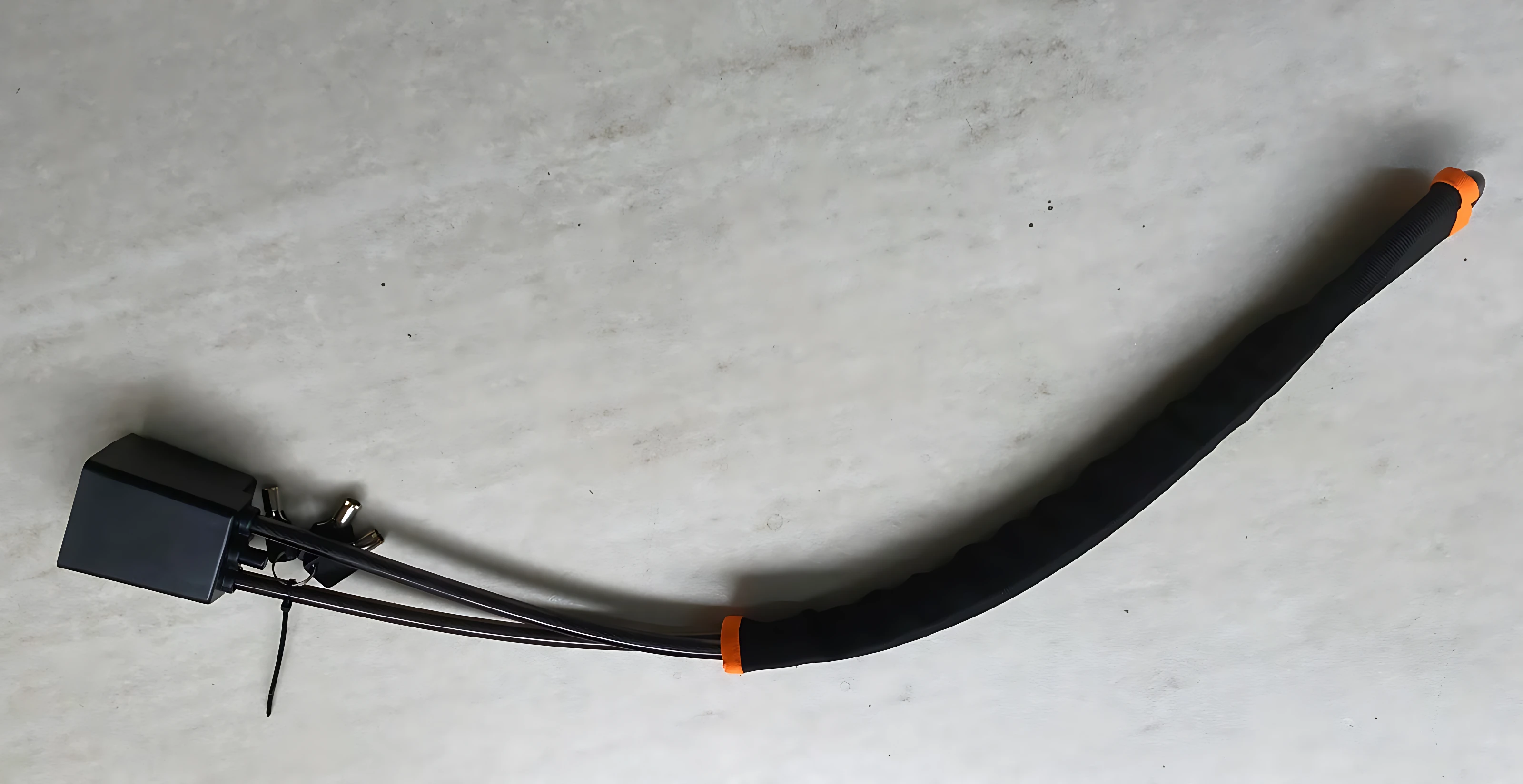 Cable de bloqueo para volante con carcasa negra y conectores naranjas, diseñado para fijar el volante y evitar su giro.