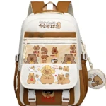 Mochila escolar blanca y marrón con estampado de capibaras, incluye compartimento frontal con ilustraciones y llavero colgante.