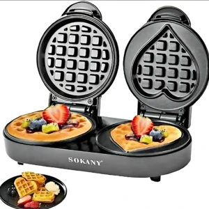 Waflera Sokany negra con placas intercambiables, mostrando forma cuadrada y corazón, con waffles decorados con frutas. Incluye plato con waffles adicionales.