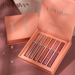 Set de seis labiales mate nude de la marca Handaiyan, presentados en caja rosa con tapas abiertas, mostrando los tubos alineados en tonos cálidos y neutros sobre fondo rosado con adornos brillantes.
