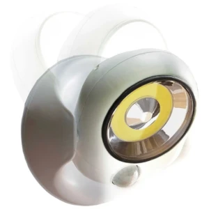 Lámpara LED exterior blanca con sensor de movimiento y fotocelda, vista frontal mostrando lente central amarilla y carcasa redondeada.