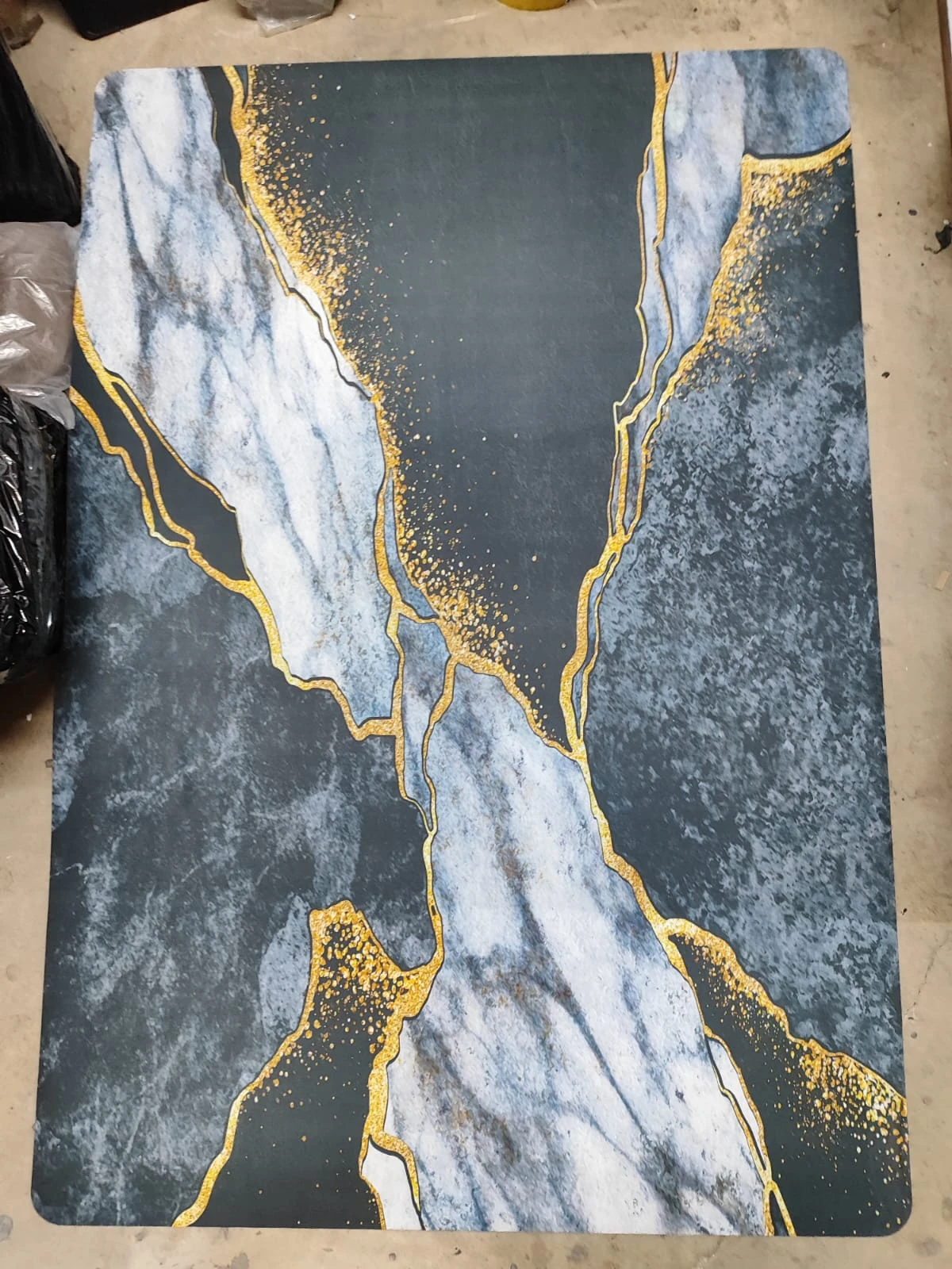 Tapete absorbente antideslizante de 30x40 cm con diseño marmolado en tonos gris, blanco y detalles dorados.