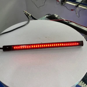 Cinta LED roja de 20 diodos encendidos, vista frontal sobre superficie blanca, con cable negro conectado al extremo izquierdo.