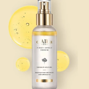 Serum spray D'Alba con trufa blanca en presentación transparente con dorado, rodeado de gotas amarillas brillantes sobre fondo crema.