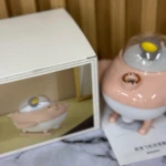 Humificador de aire en forma de nave espacial rosa pastel con cúpula transparente y base blanca, junto a su caja de presentación.