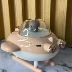Humificador de aire en forma de nave espacial, color beige y blanco, con cúpula transparente y detalles metálicos, sobre superficie de mármol.