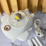 Humificador de aire blanco con diseño futurista, tapa transparente y accesorios incluidos sobre superficie de mármol.