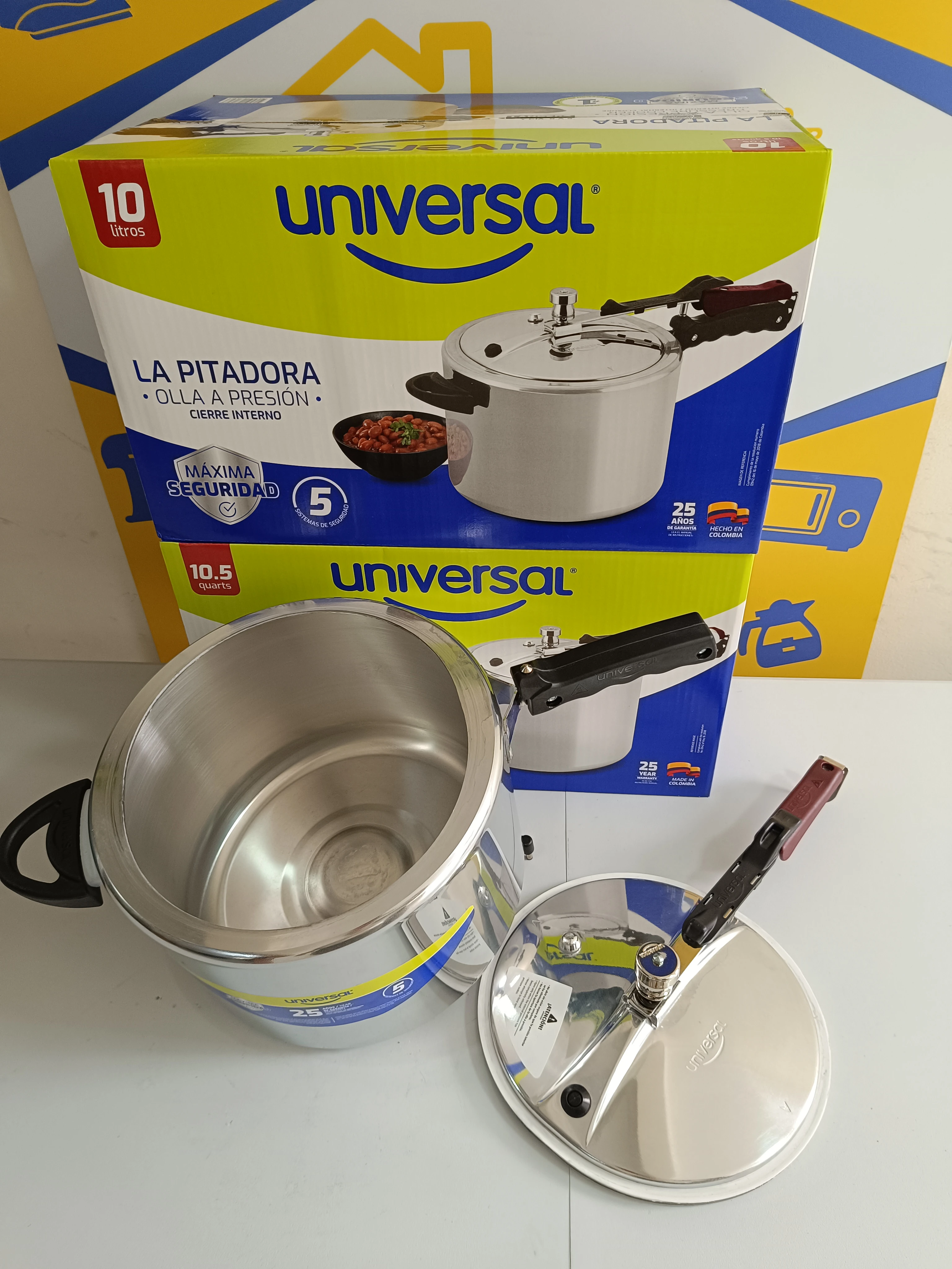 Olla a presión de aluminio de 10 litros con tapa separada, mostrada junto a su caja original. Incluye mango negro y válvula de seguridad visible.