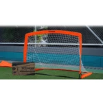 Portería de microfútbol plegable naranja con red blanca, varillas de fibra de vidrio y base estabilizadora naranja, montada sobre césped artificial con caja Wonder Sports al lado.
