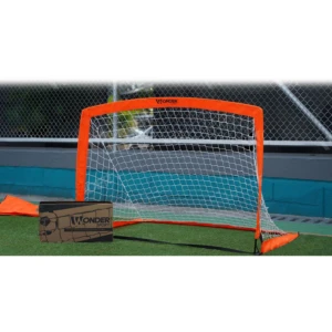 Portería de microfútbol plegable naranja con red blanca, varillas de fibra de vidrio y base estabilizadora naranja, montada sobre césped artificial con caja Wonder Sports al lado.