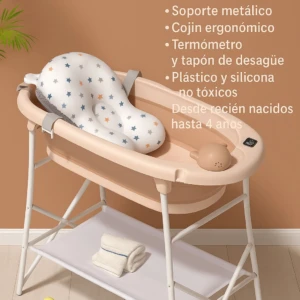 Bañera plegable color crema con base metálica blanca y cojín ergonómico estampado, sobre estante inferior con toallas y pato de goma.