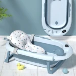 Bañera plegable para bebé con soporte en forma de ballena, color blanco con estampado de estrellas, base metálica azul y accesorios incluidos como patito de goma y pelota.