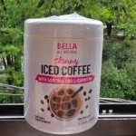 Envase blanco de café frío soluble Skinny con etiqueta rosa e de taza con hielo, sobre fondo natural difuminado.