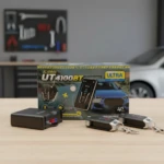 Alarma Bluetooth UT4100BT en caja con dos controles remotos y receptor negro sobre mesa de madera, fondo taller con herramientas y auto blanco desenfocado.
