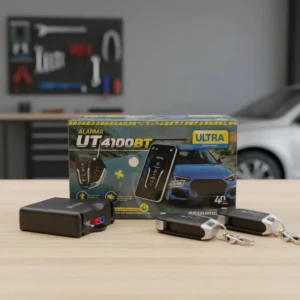 Alarma Bluetooth UT4100BT en caja con dos controles remotos y receptor negro sobre mesa de madera, fondo taller con herramientas y auto blanco desenfocado.