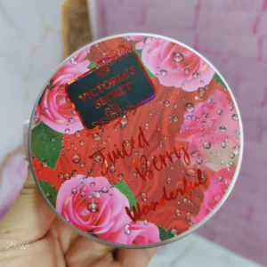 Tapa redonda de set de mantequilla corporal Victoria's Secret, diseño floral con rosas rosadas y gotas de agua, texto "Juiced Berry Wonderful" en dorado.