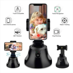 Robot selfie negro con base giratoria y soporte para celular, mostrando pantalla con niña y perro; incluye funciones de reconocimiento facial y seguimiento de objetos.