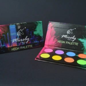 Paleta de sombras neón de Miraly abierta, mostrando seis tonos vibrantes: rosa, morado, azul, amarillo, naranja y verde. Incluye glitters y aceite de coco. Caja con diseño urbano nocturno.