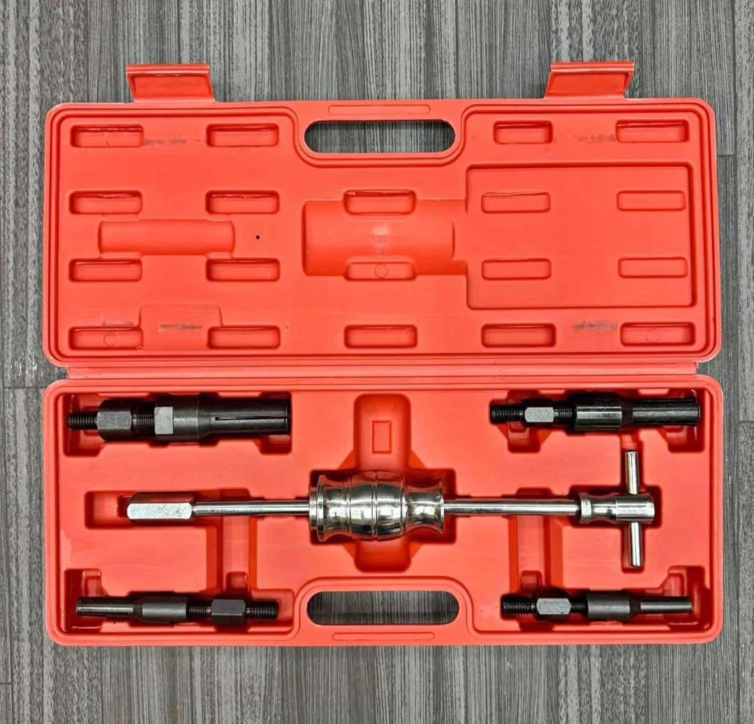 Caja naranja abierta con extractor de rodamientos interno de 5 piezas, incluyendo herramienta principal y accesorios, sobre superficie gris texturizada.